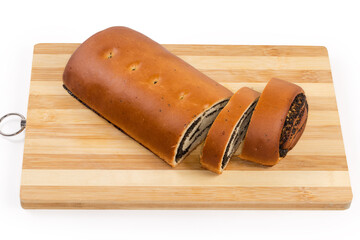 Partly sliced poppy seed roll on the wooden cutting board