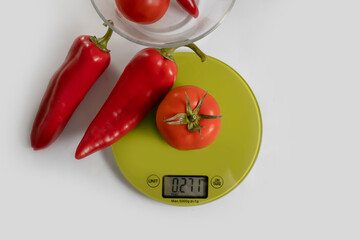 kitchen scales tomato, pepper on a light background
