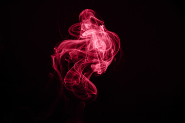 Unusual red smoke on a black background. Color of the year 2023 - Viva Magenta