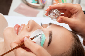 Make-up artist makes the procedure of lamination and dyeing of eyelashes to a beautiful woman in a...