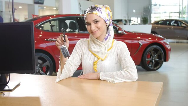 The concept of the rights and independence of women in Islam. Happy woman in hijab receiving keys from purchased car