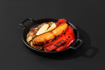 salmon steak with grilled vegetables on a black background