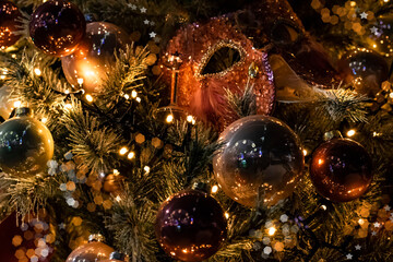 Fototapeta na wymiar Blurred dark Christmas tree background with masquerade mask and festive lights, soft focus.