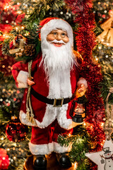 Santa Claus with gifts on the background of the Christmas tree. Christmas background in red and gold colors in vertical format.