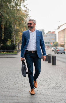 A Handsome Mature Business Man Is Walking Through The City Street.