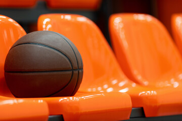 Brown basketball ball on orange bench in arena. Horizontal sport poster, greeting cards, headers, website