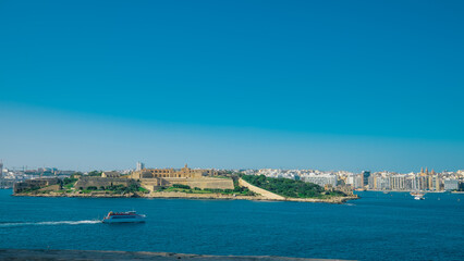 Ferry betweem Sliema and Valletta on malta visible sailing towards sliema in evening hours, cityscape of valletta in the background.