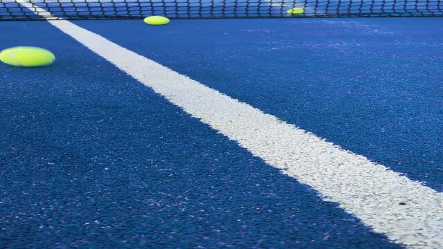 vertical video, balls bouncing on a blue paddle tennis court