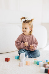 girl plays toys in living room. Montessori wooden toy folded pyramid. Circle, triangle, rectangle...