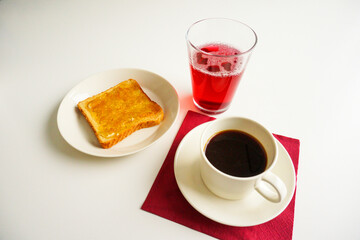 Breakfast with hot coffee, toast with orange marmalade and a glass of homemade currant juice. Red napkin and white table. Top view image.
