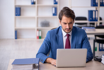 Young male employee and too much work in the office