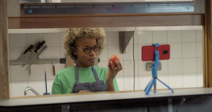 African American female chef recording a video tutorial in a kitchen.