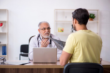 Young male doctor visiting old male doctor radiologist