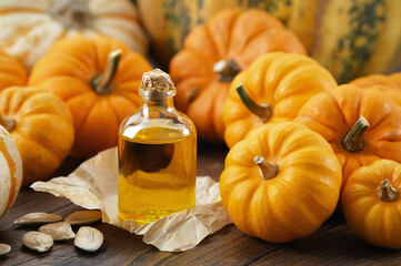 Healthy pumpkin seeds oil bottle, pumpkins on wooden kitchen table.