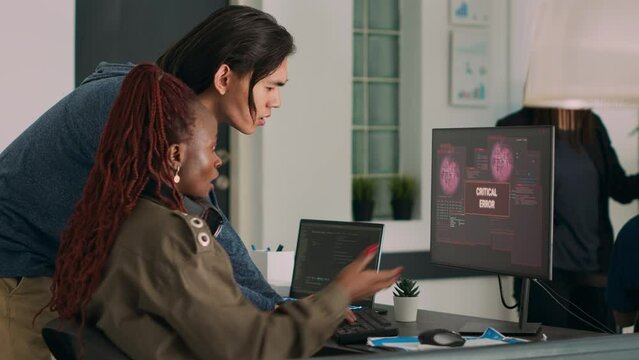 Diverse team of coders dealing with security breach alert on computer, trying to solve hacking and critical error. Engineers using terminal window and having system hacked crash.