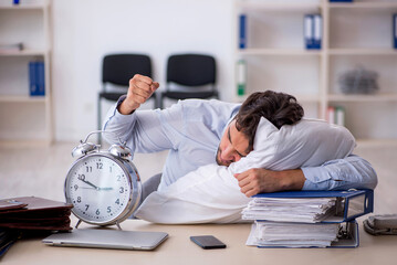 Young male employee in oversleeping concept