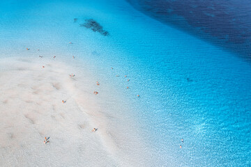 Fototapeta na wymiar Aerial view of amazing sea coast. Top view from drone of beach with white sand, swimming people in blue transparent water at sunny day. Summer in La Pelosa beach, Sardinia, Italy. Tropical landscape