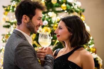 Couple holding glasses with champagne celebrating Christmas winter holidays at home together, wish luck and joy. Celebration concept.