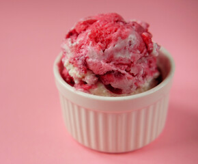 Bowl of pink strawberry ice cream and fresh berries isolated on pink background.