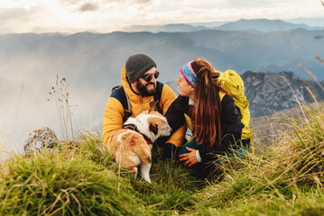 couple of hikers in love, looking into each other's eyes and stroking a dog. A couple doing...