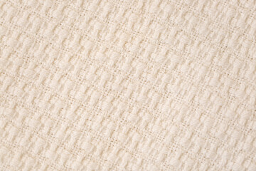 Beige knitted throw fabric texture background. Closeup