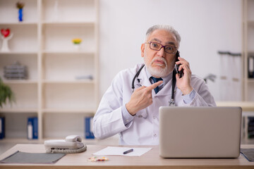 Old male doctor in telemedicine concept