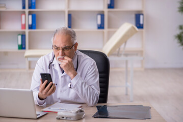 Fototapeta premium Old male doctor in telemedicine concept