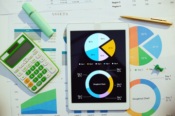 tablet pc, calculator, documents and graphs at desk