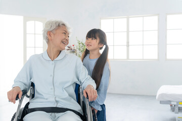 Obraz premium 車椅子に乗った高齢者をお見舞いする女の子