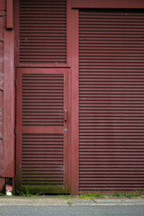 Fototapeta na wymiar Building facade. Abstract, locked metal door and security shutter to a loading dock or garage. Corrugated ribbed metal texture painted brown. Interesting texture. 