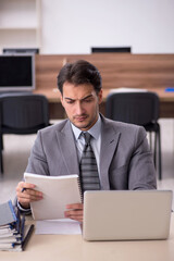 Young male employee unhappy with excessive work in the office