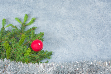 Gray background with fir branch, red christmas ball and silver garland with copy space