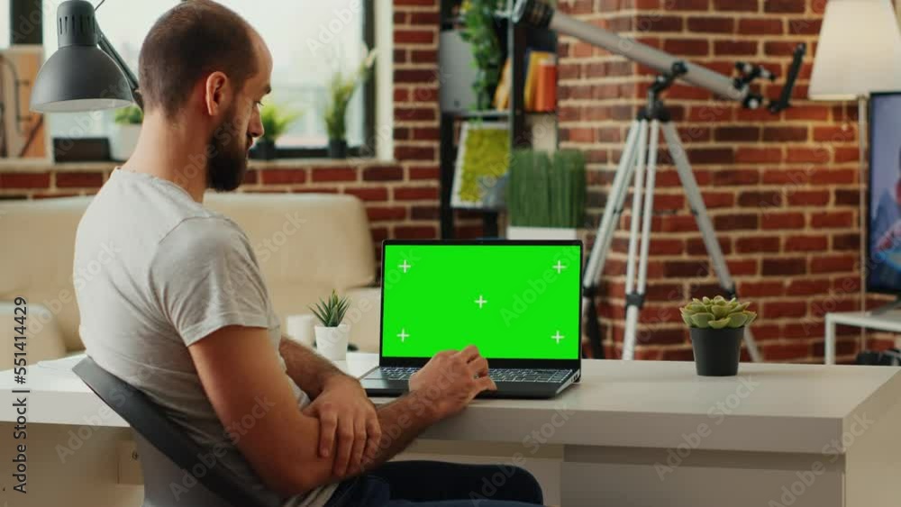 Poster office employee looking at laptop with greenscreen display and analyzing blank chroma key template o