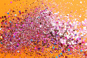 Shiny bright pink glitter on orange background, flat lay