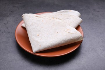 Delicious folded Armenian lavash on dark table