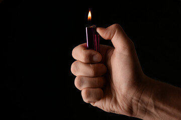 Man holding lighter on black background, closeup. Space for text - obrazy, fototapety, plakaty