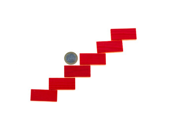 Fototapeta premium Euro coin rise up. One euro coin on a red step ladder isolated on a white background.