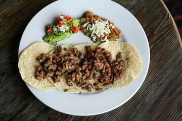 Plate with delicious tacos served on wooden table, top view