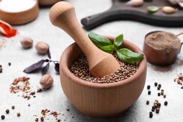 Mortar with pestle and different spices on light grey table, closeup