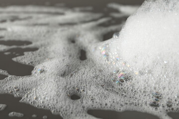 Fluffy bath foam on grey background, closeup