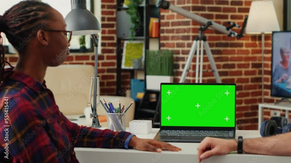 Aufkleber multiethnic team of man and woman analyzing greenscreen display on laptop, using blank chroma key te