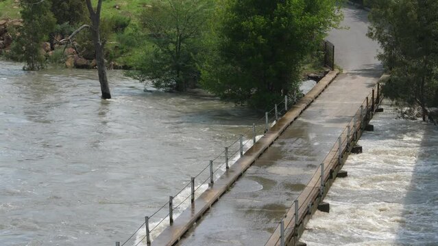 Flood water of muddy fast river at deck of low single lane bridge