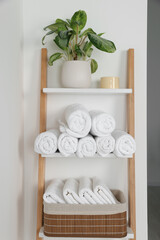 Soft towels on decorative ladder near white wall
