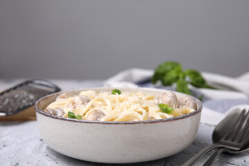 Delicious pasta with mushrooms and cheese served on light grey textured background, closeup