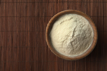 Bowl of agar-agar powder on bamboo mat, top view. Space for text