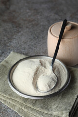 Bowl, spoon and box of agar-agar powder on grey table