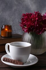 Beautiful pink chrysanthemum flowers and cup of aromatic tea with sweet chocolate cookie on wooden table