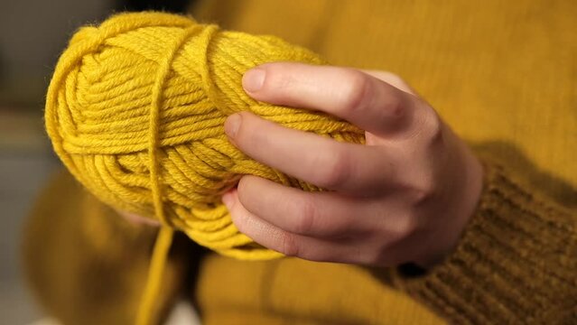 Knitting concept.Hands winding a woolen skein yellow yarn close-up. Hobby and needlework concept. Knitting warm clothes with your own hands. High quality 4k footage