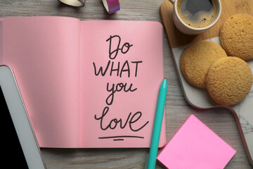 Open notebook with motivational phrase Do What You Love, cookies and coffee on wooden table, flat...