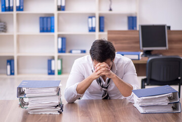 Obraz premium Young male employee unhappy with excessive work at workplace
